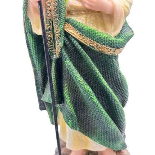 Green fabric with gold trim held by a hand on a white background