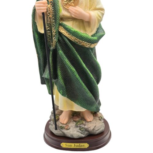 Statue of a religious figure in green and gold robes holding a staff on a white background